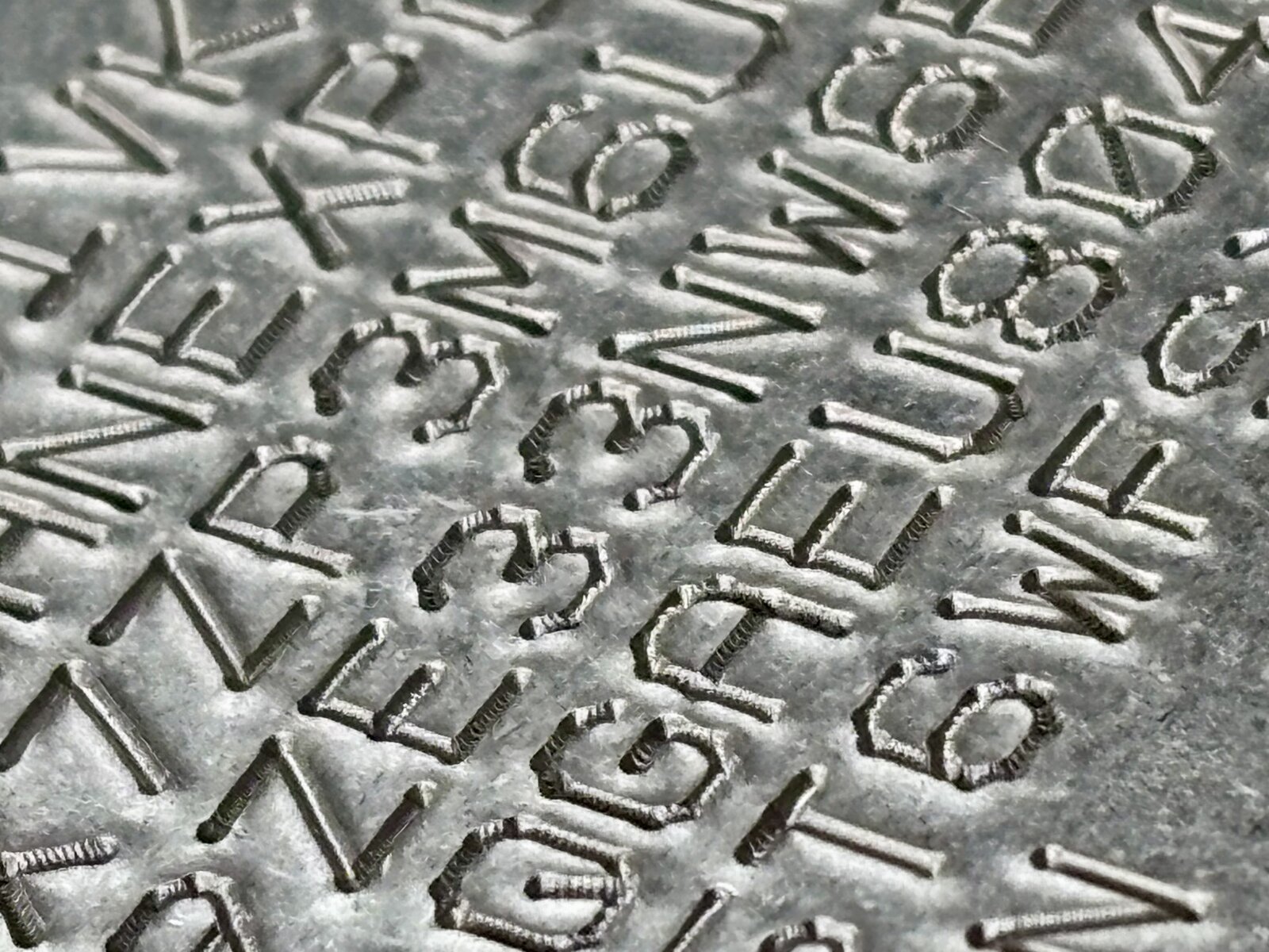 Macro photograph of an engraved Nostr nsec plate; the monospaced font catches a low side light, tool marks visible in each cut.